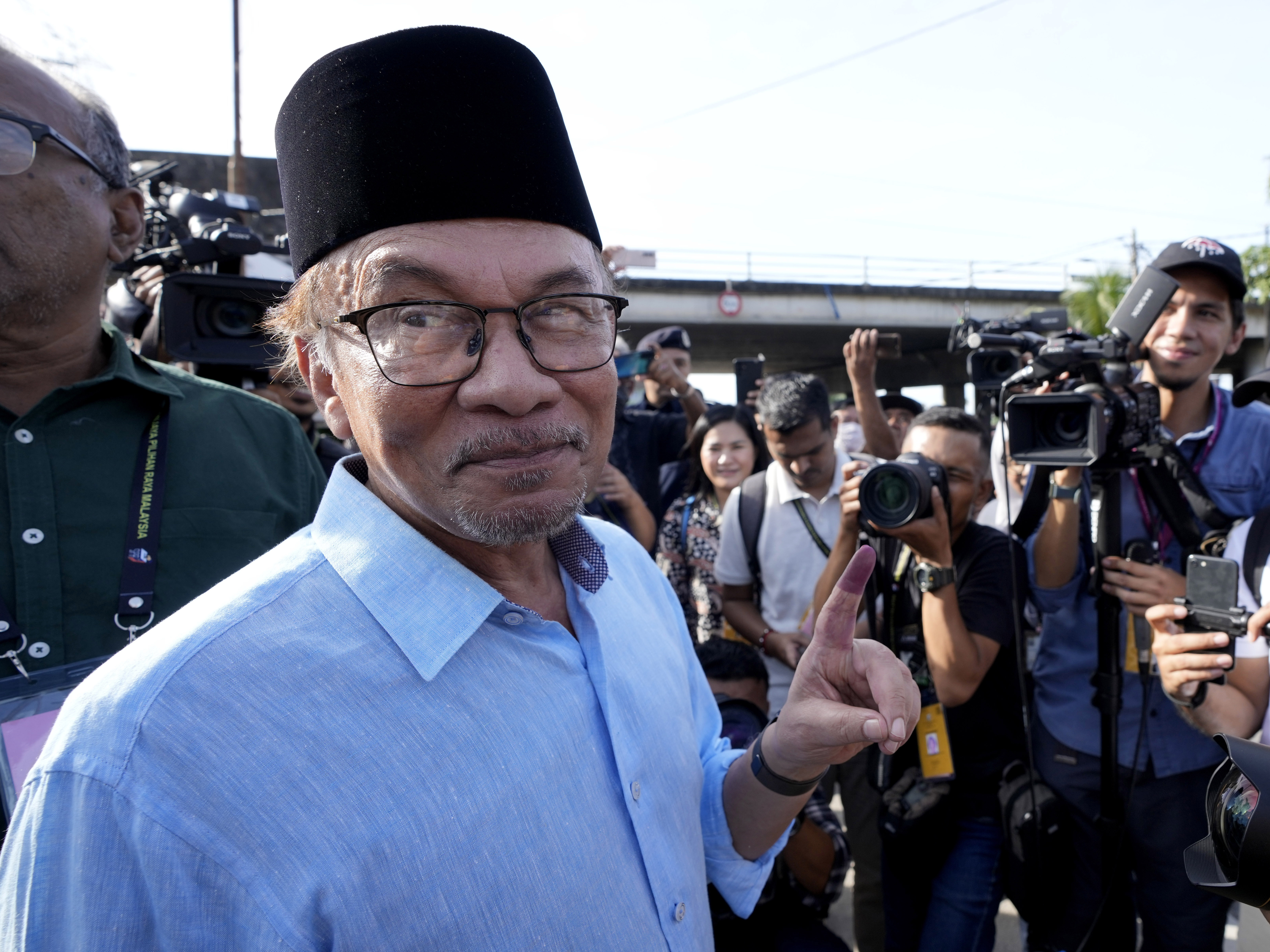 caption: Opposition leader Anwar Ibrahim shows his inked finger to the media after voting at a polling station in Seberang Perai, Penang state, Malaysia on Nov. 19, 2022.