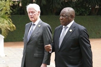 caption: Former US President Bill Clinton, left, and South Africa's President Cyril Ramaphosa arrive to lay a wreath at a ceremony to mark the 30th anniversary of the Rwandan genocide, held at the Kigali Genocide Memorial, in Kigali, Rwanda, Sunday, April 7, 2024. Rwandans are commemorating 30 years since the genocide in which an estimated 800,000 people were killed by government-backed extremists.