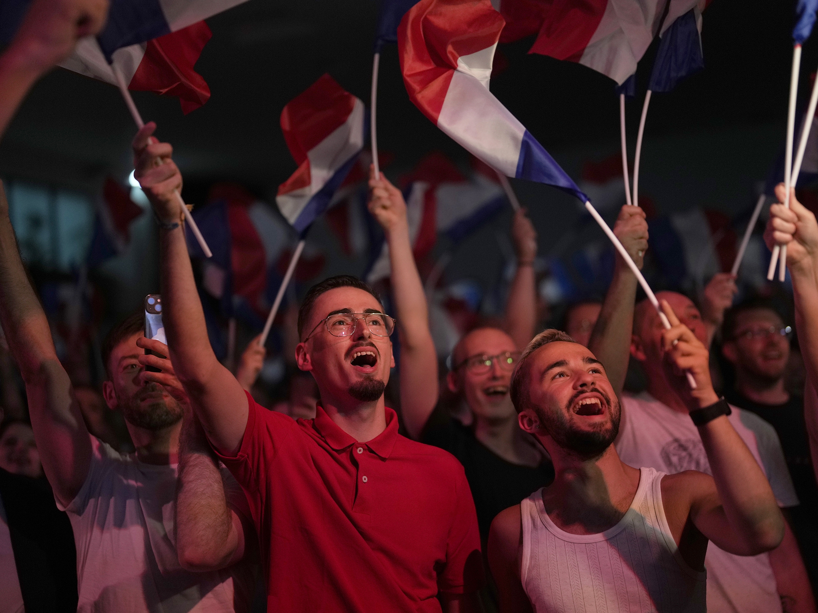 caption: Supporters of French far-right leader Marine Le Pen react after vote projections in select constituencies, Sunday, in Henin-Beaumont, northern France. French voters propelled the far-right National Rally to a strong lead in first-round legislative elections Sunday and plunged the country into political uncertainty.