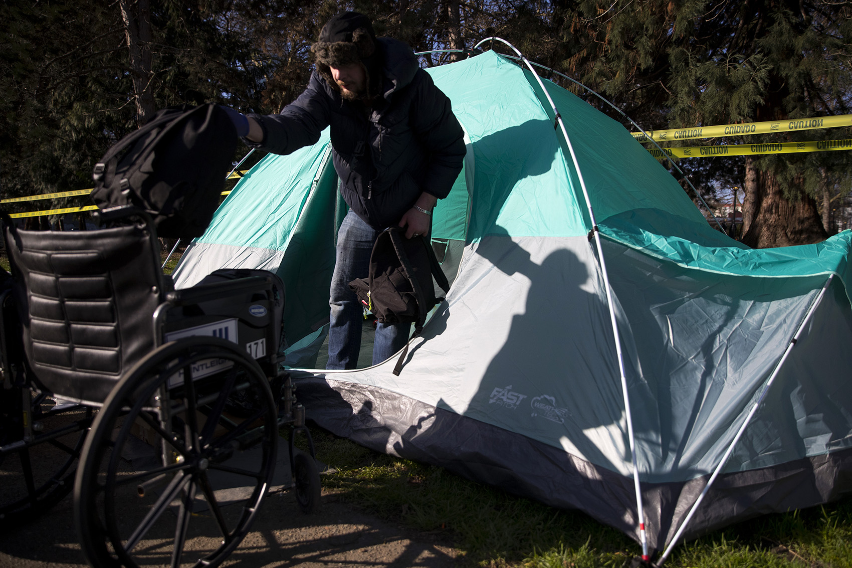 caption: Robert DeWitt moves belongings out of his tent as Seattle police and Parks and Recreation swept unhoused people from Denny Park on Wednesday, March 3, 2021, in Seattle. DeWitt had stayed overnight hoping to speak with outreach services but was only approached by police.