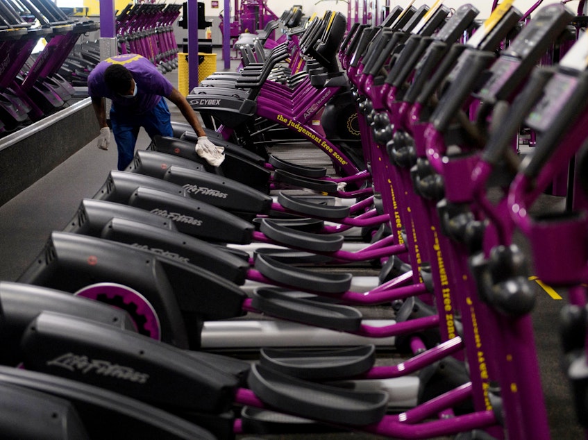 caption: A Planet Fitness Inc. employee cleans gym equipment before the location's reopening on March 15, after being closed due to Covid-19 in Inglewood, California.