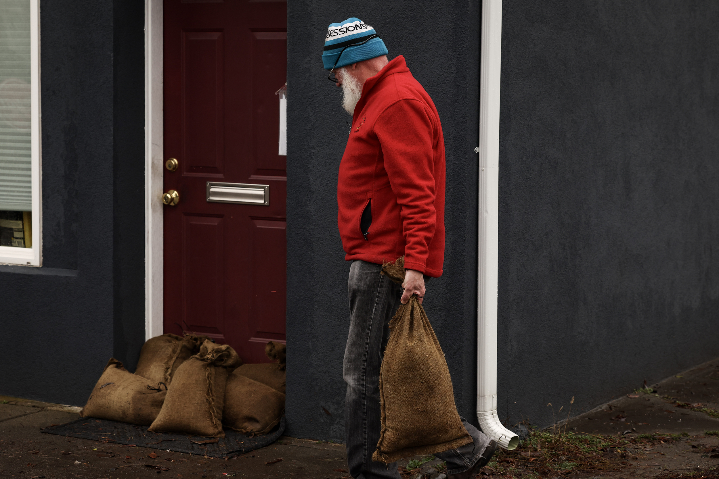 caption: A resident of Snoqualmie is seen getting ready for historic flooding with sandbags on December 11, 2025, in Snoqualmie. 