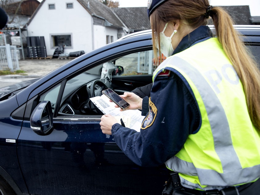 caption: An Austrian police officer checks a driver's vaccination certificate during a traffic control stop in Graz, Austria, on Monday.