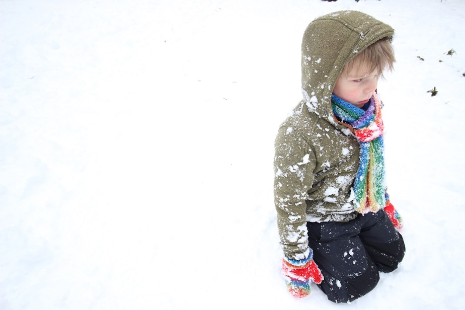 caption: Oscar Pulkkinen, 5, sits in the snow after being pelted with snowballs.