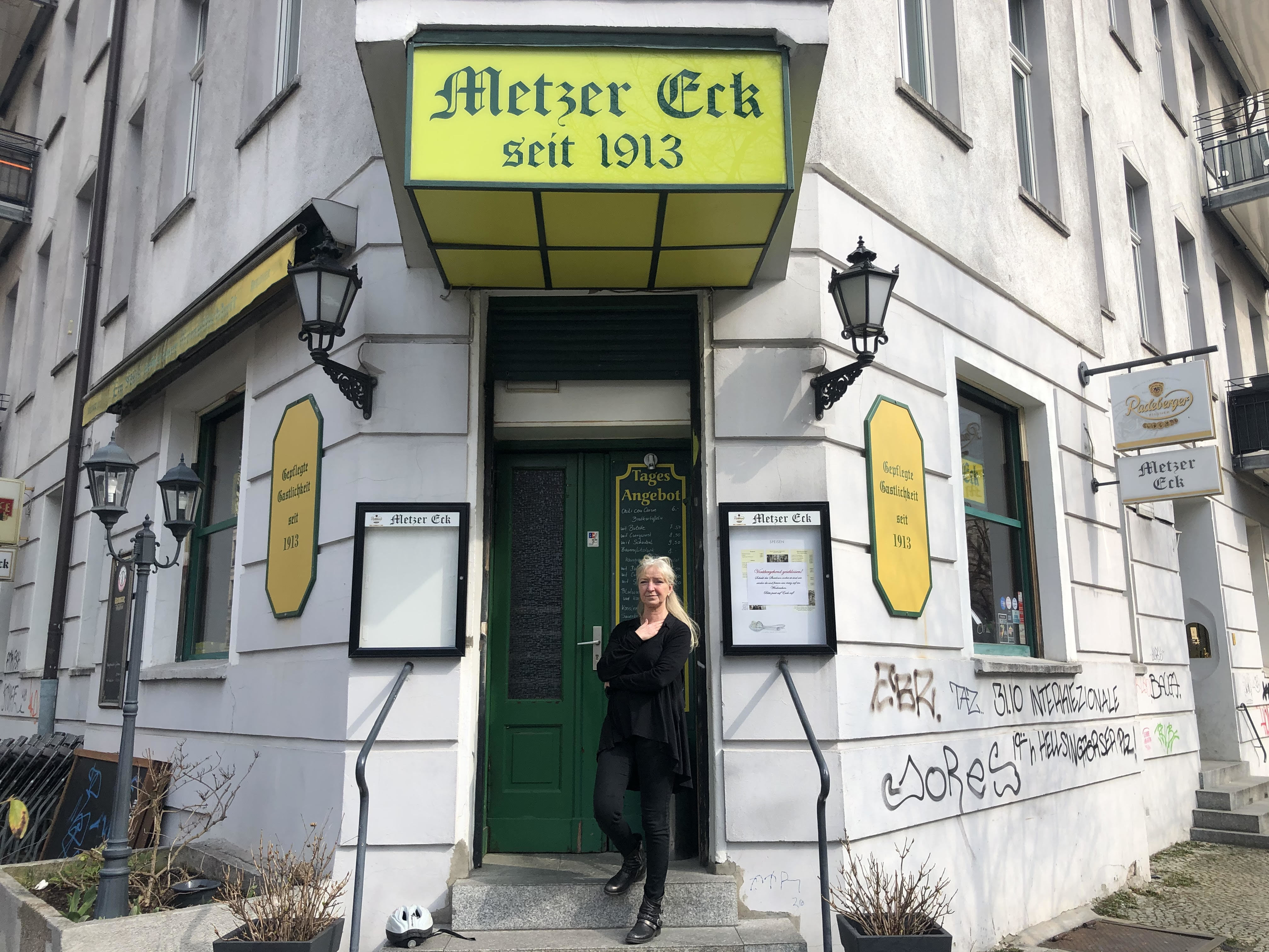 caption: Sylvia Falkner stands in front of her Berlin pub, Metzer Eck, which has been owned by four generations of the same family since 1913. She is one of thousands of small German business owners struggling to keep their businesses open in an extended pandemic lockdown.