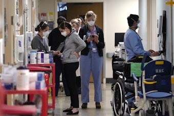 caption: Medical workers fill a hallway in the acute care unit, where about half the patients are Covid-19 positive or in quarantine after exposure, of Harborview Medical Center, Friday, Jan. 14, 2022, in Seattle. Washington. 