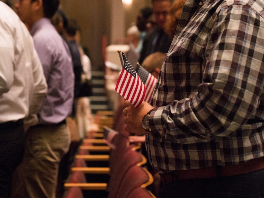 caption: Newly sworn-in U.S. citizens rise from their seats during a 2018 naturalization ceremony in Alexandria, Va.