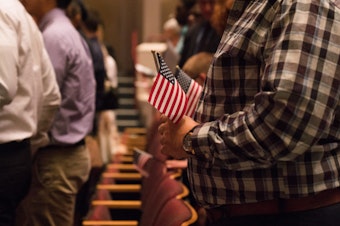 caption: Newly sworn-in U.S. citizens rise from their seats during a 2018 naturalization ceremony in Alexandria, Va.