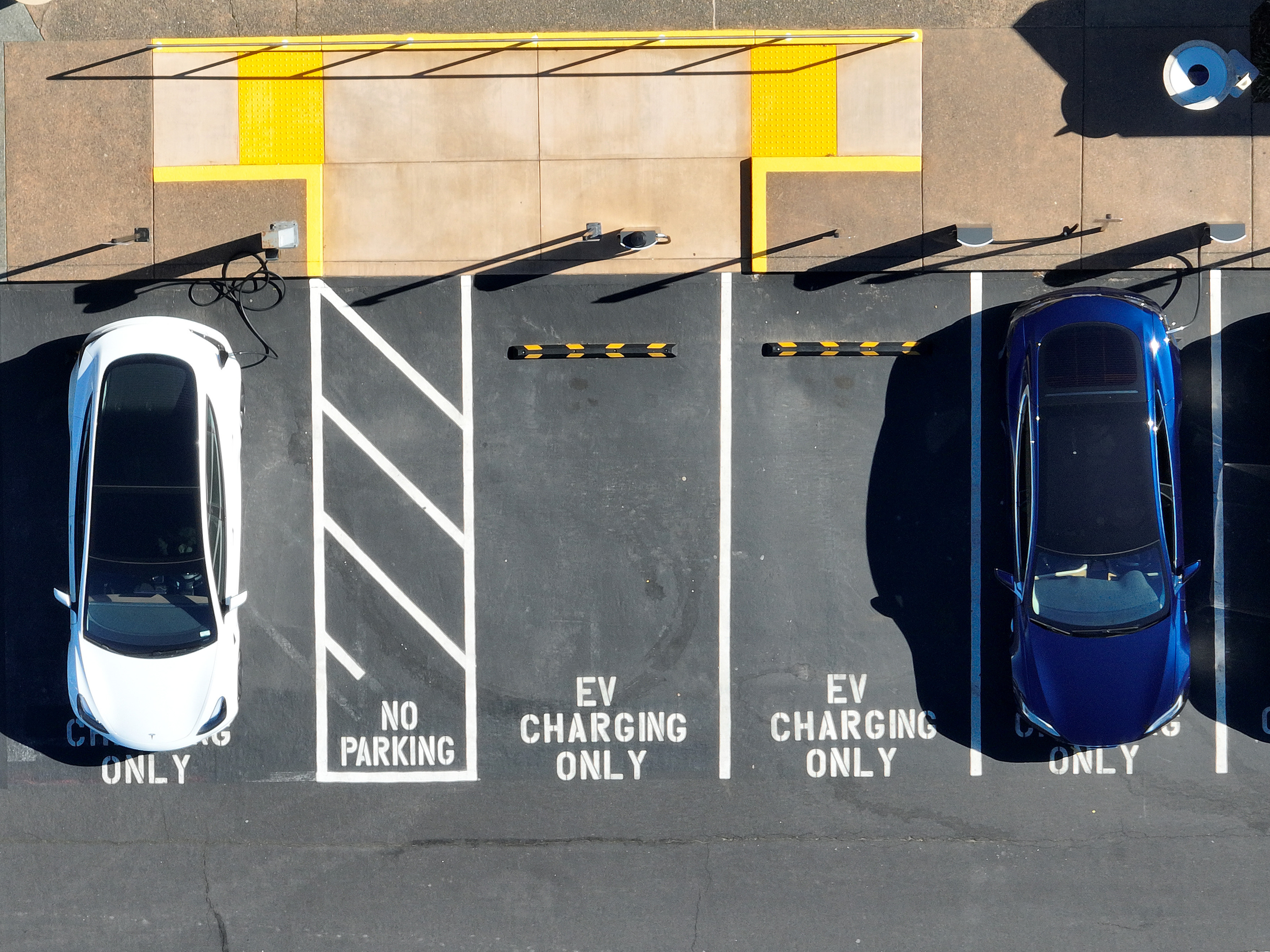 caption: Tesla vehicles recharge in February in Corte Madera, Calif. The government wants to accelerate the transition to electric vehicle, but how fast the country can actually move is being hotly debated.