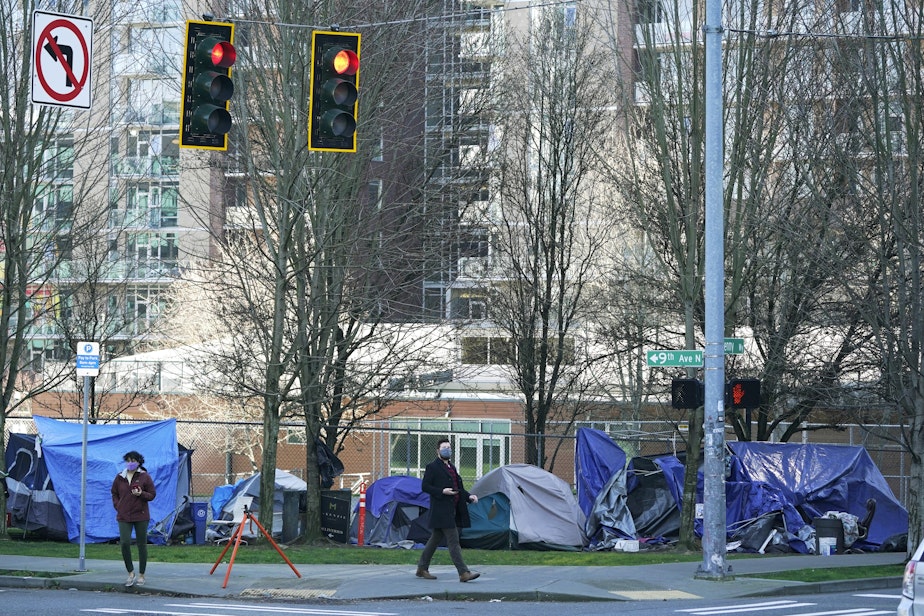 caption: In this March 3, 2021, file photo, with apartment buildings in the background, pedestrians walk past tents used by people lacking housing at Denny Park near the Space Needle in Seattle. A Washington state judge on Friday, Aug. 27, 2021, struck a Seattle measure on homelessness from the November ballot even as the city remains mired in a long-term humanitarian crisis.