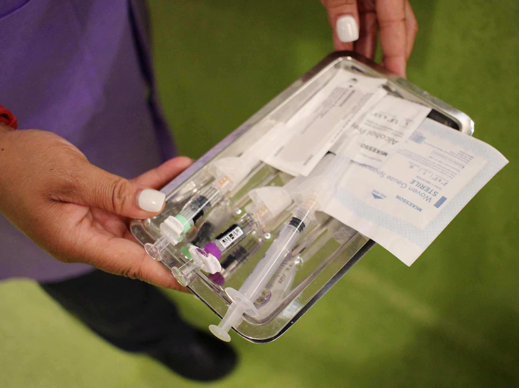 caption: Band-aid at the ready, Sara McRae, a medical assistant at Unity Health Care, heads in to vaccinate a pediatric patient.