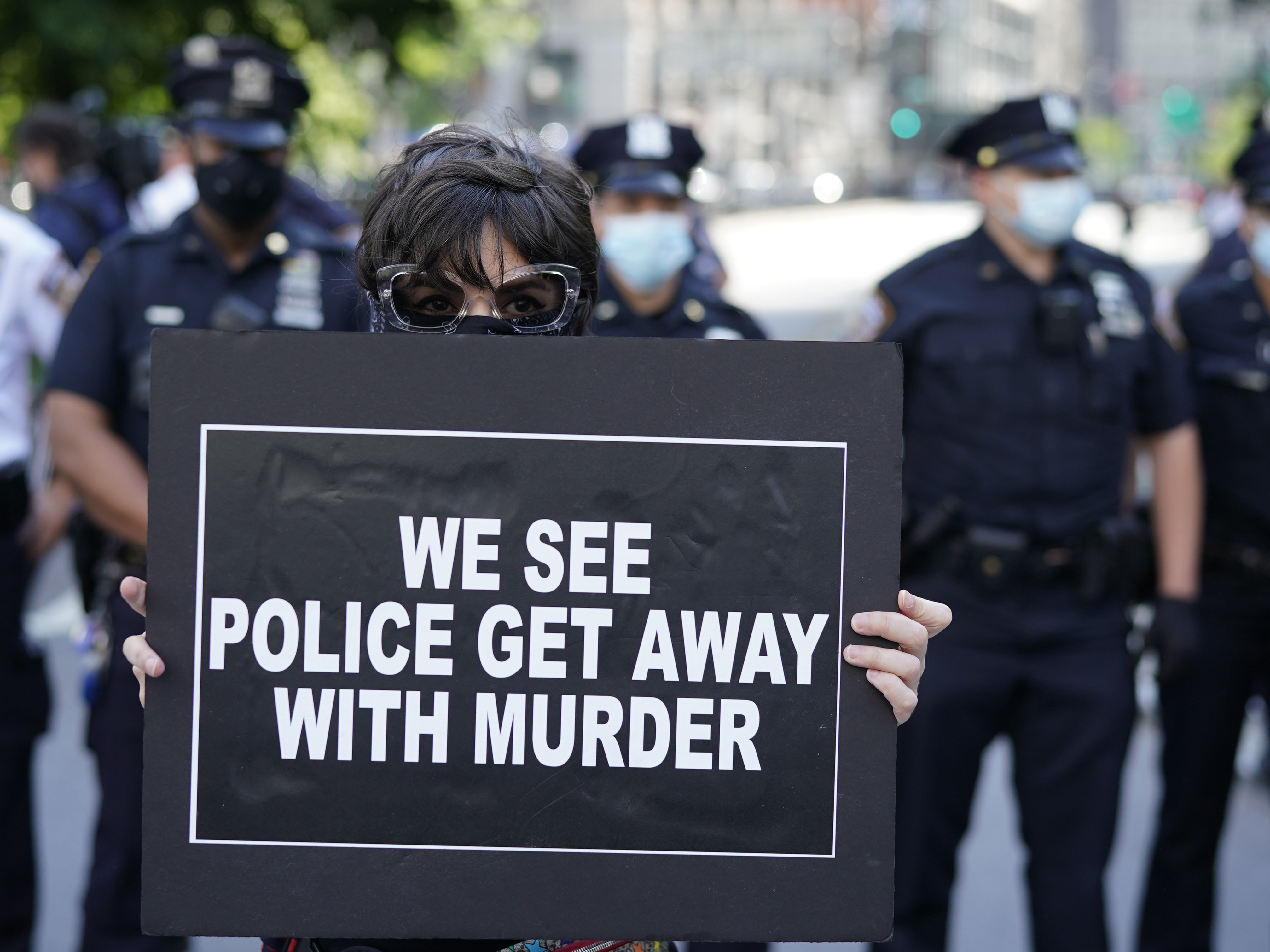 caption: New York City Police officers stand behind a protester during a vigil at Foley Square in New York last month.