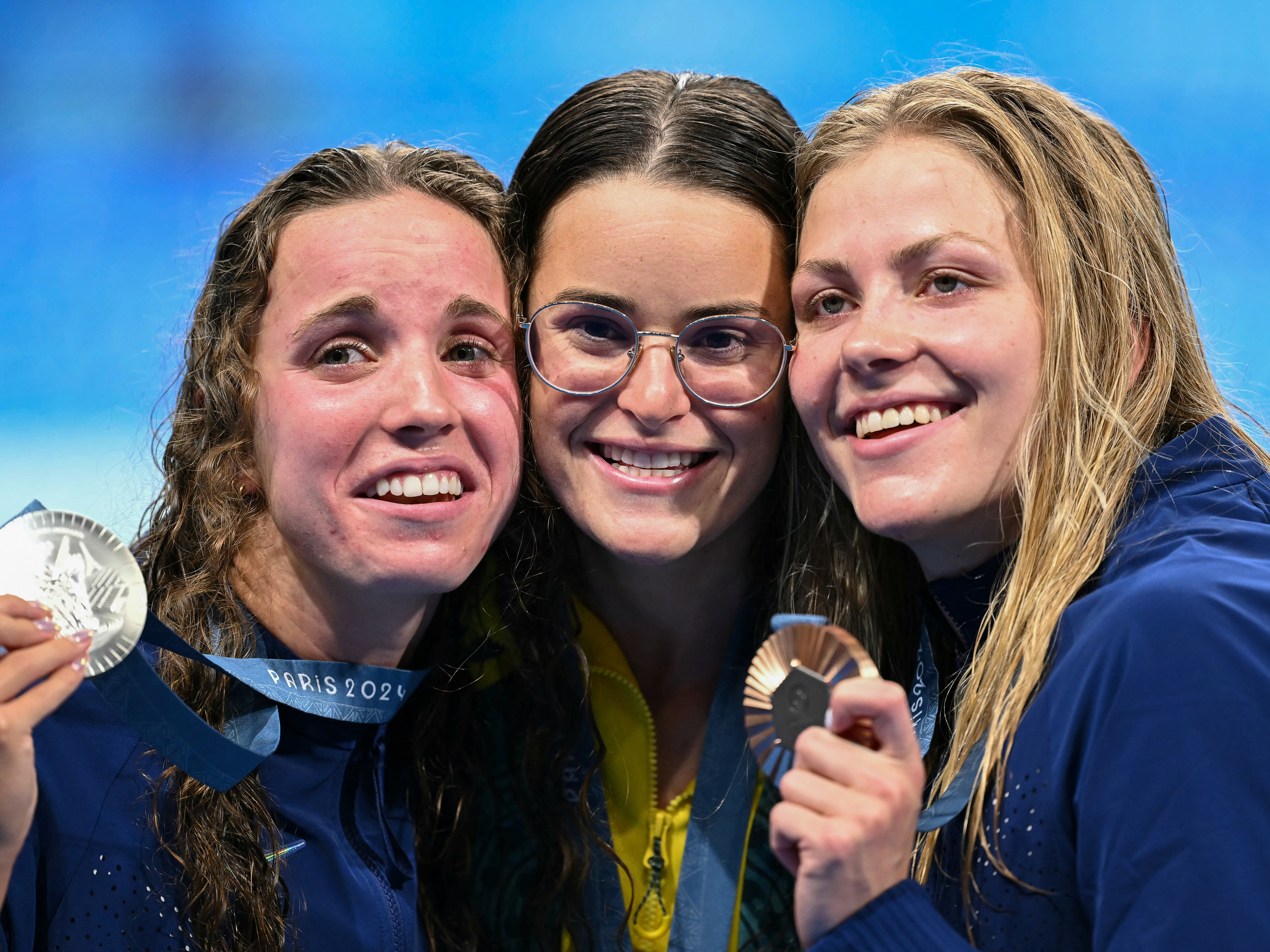 caption: From left, U.S. silver medalist Regan Smith, Australian gold medalist Kaylee McKeown and U.S. bronze medalist Katharine Berkoff pose with their medals following the women's 100-meter backstroke swimming event during the Paris 2024 Olympic Games on Tuesday. Berkoff's bronze was not only the 3,000th medal for Team USA, but also the 600th Olympic medal earned by a USA swimming athlete.