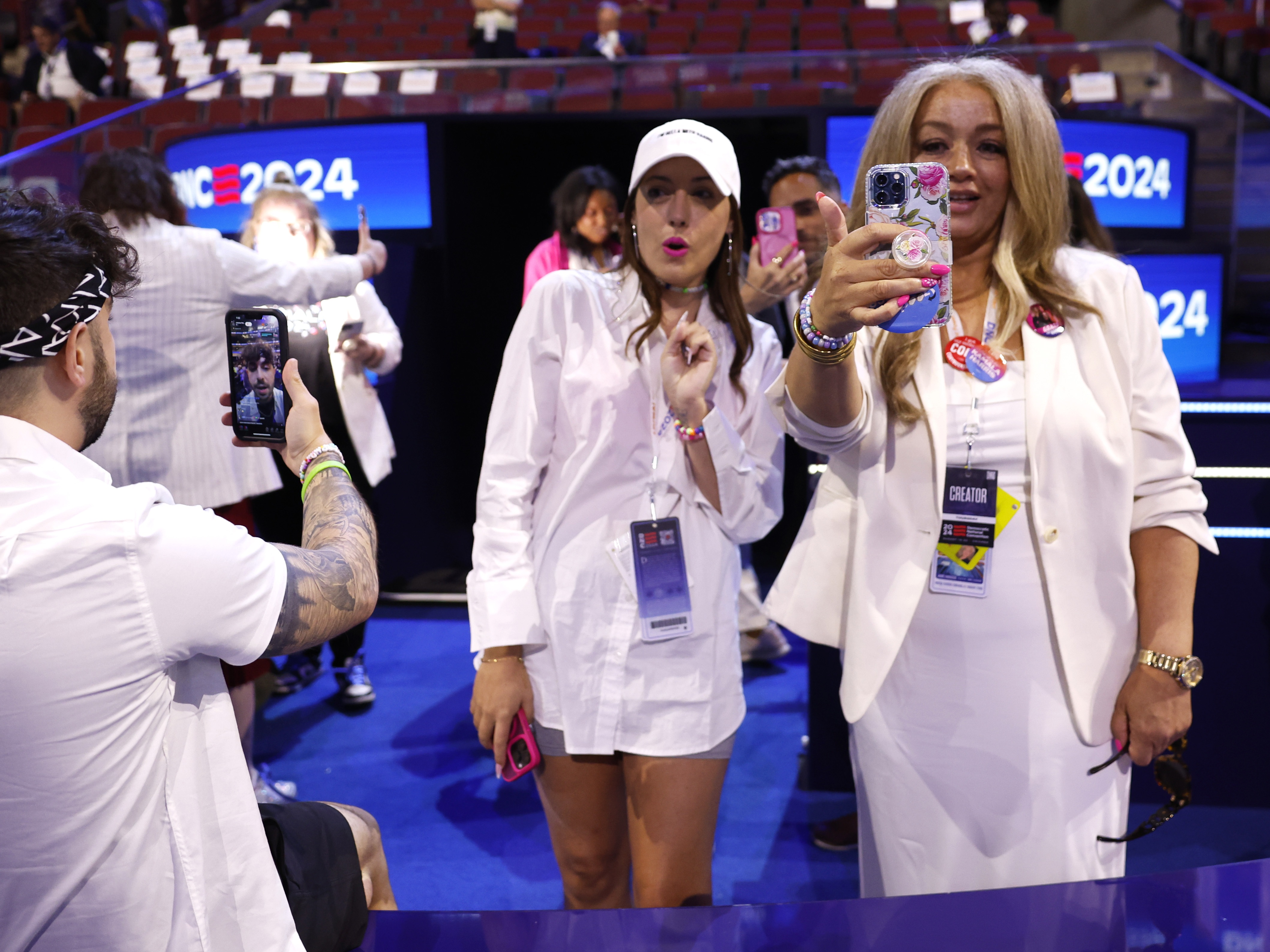 caption: Social media influencers wearing white produce content during the final day of the Democratic National Convention in Chicago on Aug. 22, 2024.