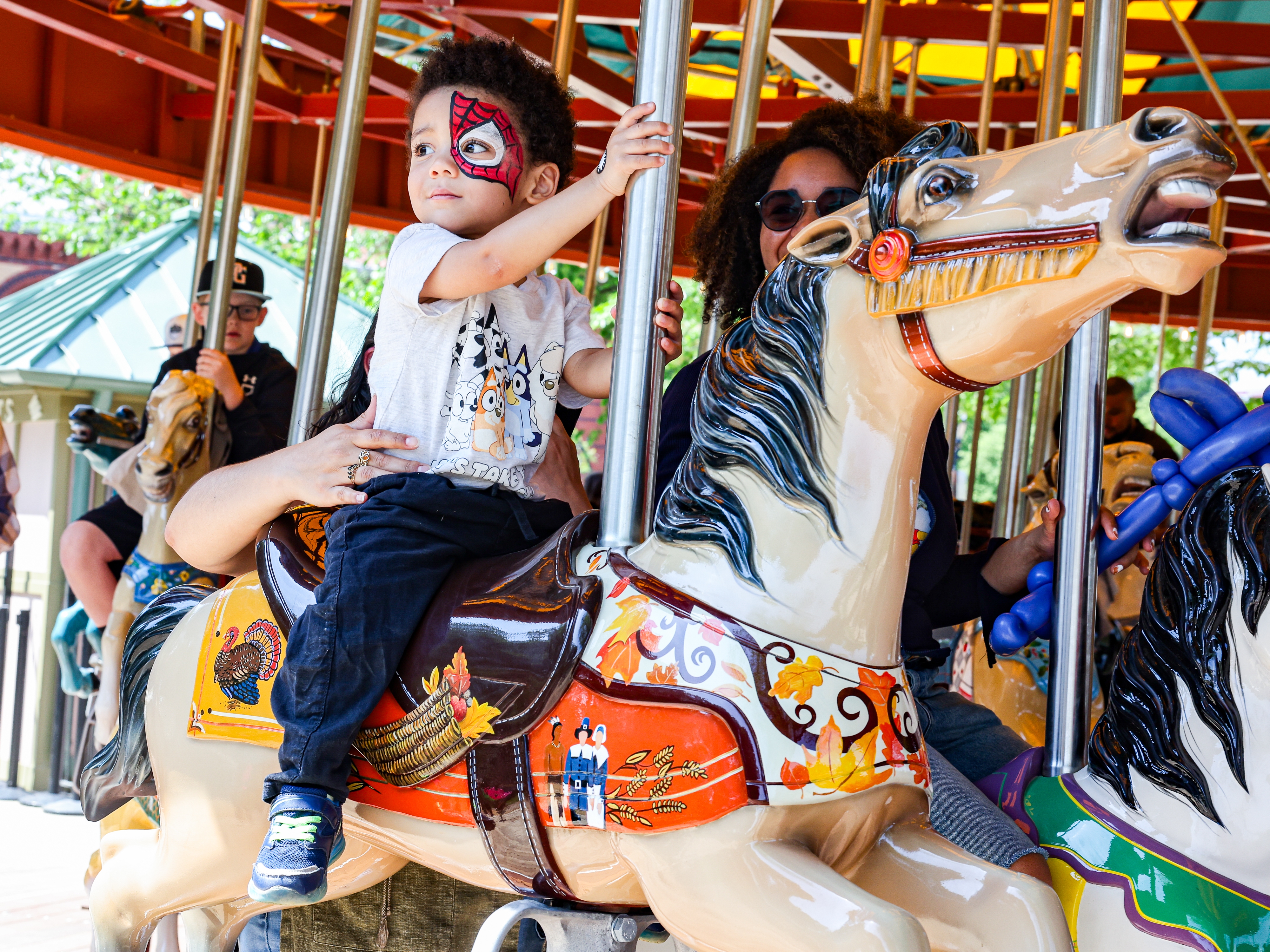 caption: Denay Wilkerson and her son Cairo, 2, ride the newly restored Smithsonian National Carousel on the National Mall in Washington, D.C., on Thursday.