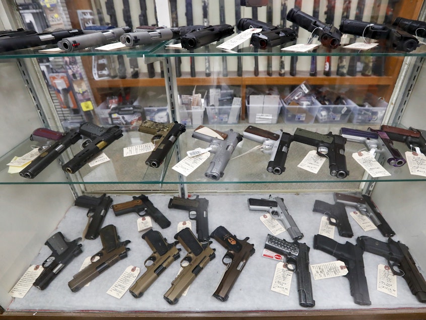 caption: The FBI has reported a surge in background checks for gun sales. Here, firearms are for sale at a shop in New Castle, Pa.