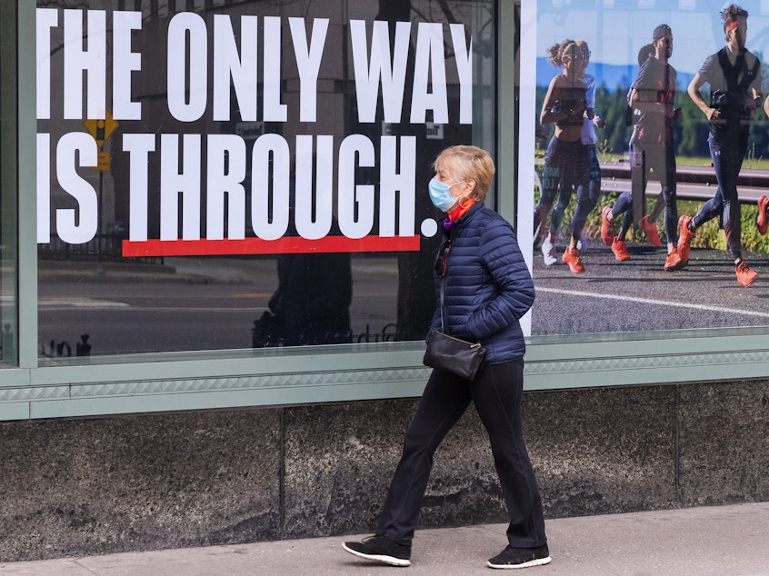 caption: Majorities of all major political groups say they support shelter-in-place orders to fight the COVID-19 pandemic, according to a recent poll. Here, a person wearing a face mask walks down a mostly empty Michigan Avenue in Chicago Thursday.