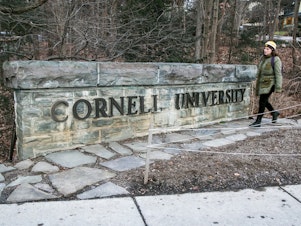 caption: A woman walks by a Cornell University sign on the Ivy League school's campus in Ithaca, New York, on Jan. 14, 2022. Cornell University administrators dispatched campus police to a Jewish center after threatening statements appeared on a discussion board Sunday, Oct. 29, 2023.
