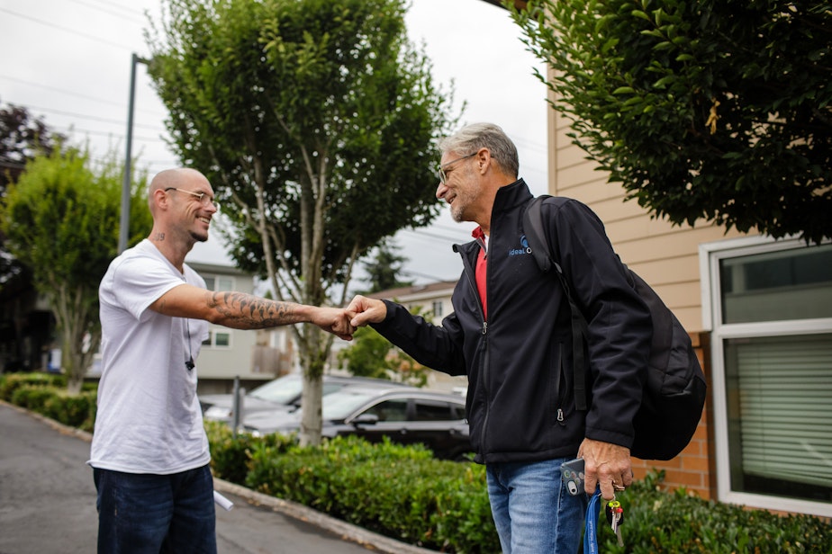 caption: Geoff Godfrey (right) greets a patient outside the Ideal Option clinic in Everett, Wash. (Finding Fixes)