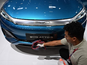 caption: A man polishes an Atto 3 car from Chinese car maker BYD at the International Motor Show (IAA) in Munich, Germany, on Sept. 4, 2023. The car has gained in popularity among Europeans.