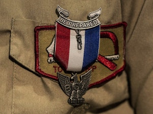 caption: An Eagle Scout Award is seen pinned to a uniform. After a lengthy sex-abuse scandal and bankruptcy, the Boy Scouts are changing their name to Scouting America.