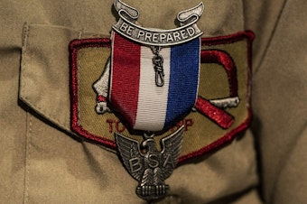 caption: An Eagle Scout Award is seen pinned to a uniform. After a lengthy sex-abuse scandal and bankruptcy, the Boy Scouts are changing their name to Scouting America.