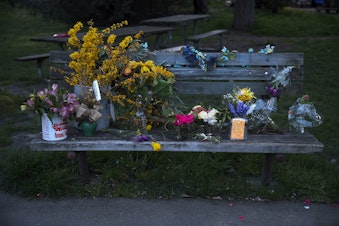 caption: Flowers are left on a bench near the Leschi Market in honor of co-owner Steve Shulman, who passed away on March 18 as a result of the coronavirus, on Monday, March 23, 2020, in Seattle.