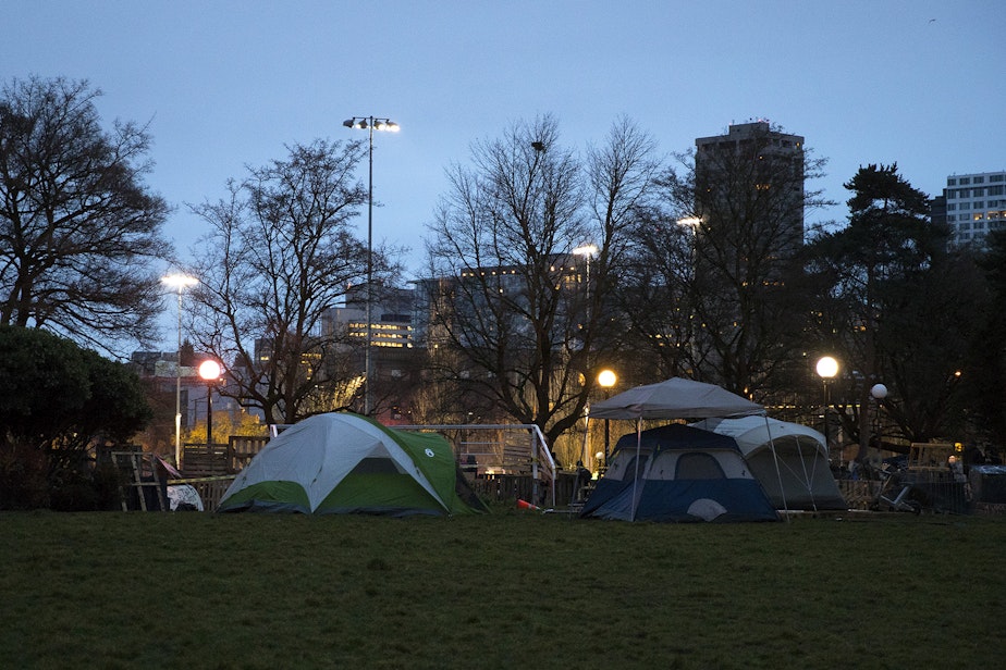 caption: Tents are shown near a barricade set up around the perimeter of an encampment where unhoused community members reside on Wednesday, December 16, 2020, ahead of a scheduled sweep by the Seattle Police Department at Cal Anderson Park in Seattle. 