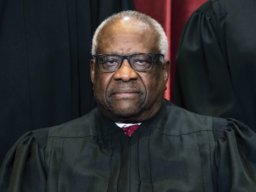 caption: Justice Clarence Thomas sits during a group photo at the Supreme Court in Washington, on Friday, April 23, 2021.