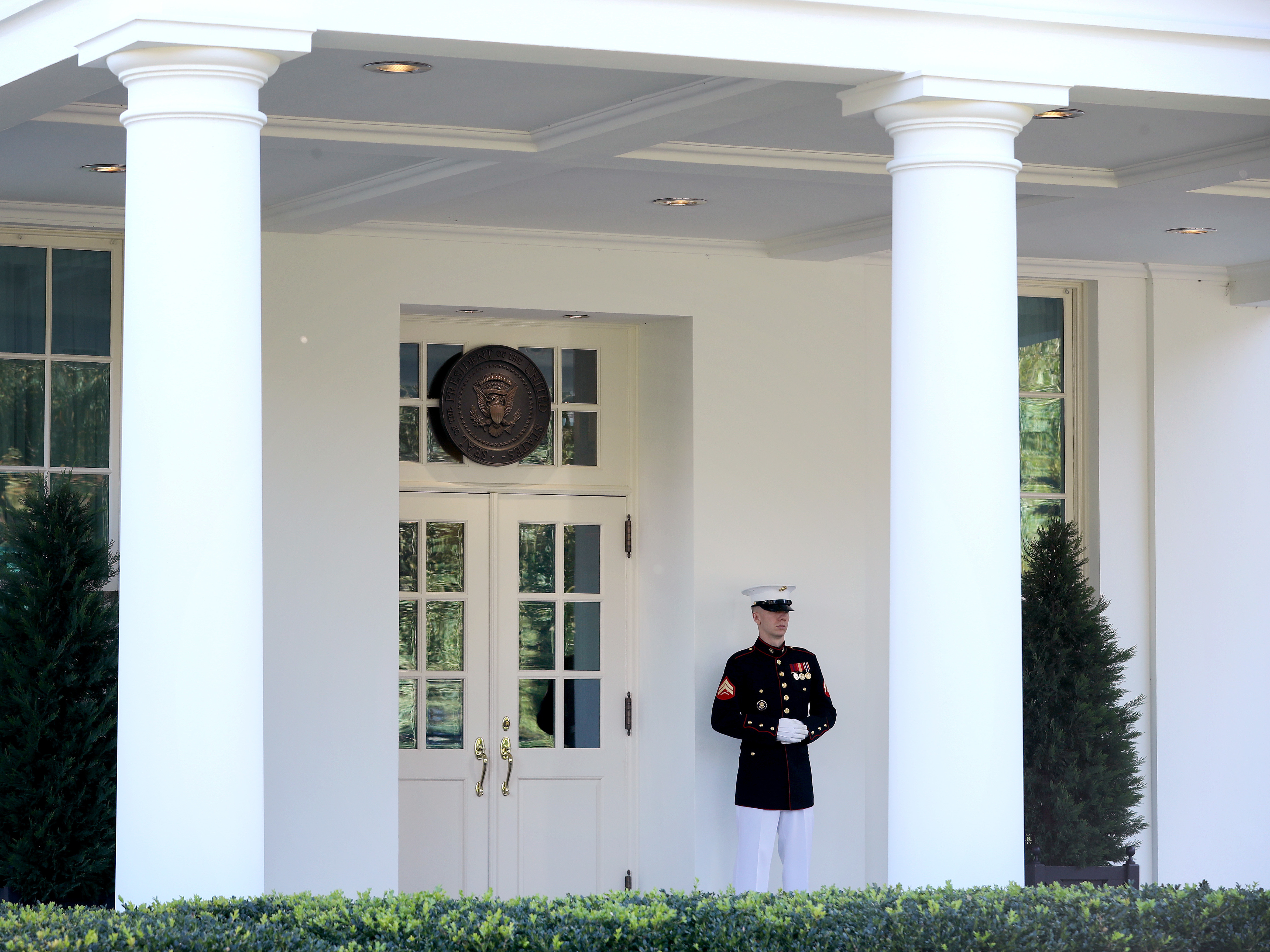 caption: A U.S. Marine stands watch outside the doors of the White House West Wing on Wednesday. According to the White House, President Trump was in the Oval Office Wednesday afternoon, even as he continues to be monitored for COVID-19.