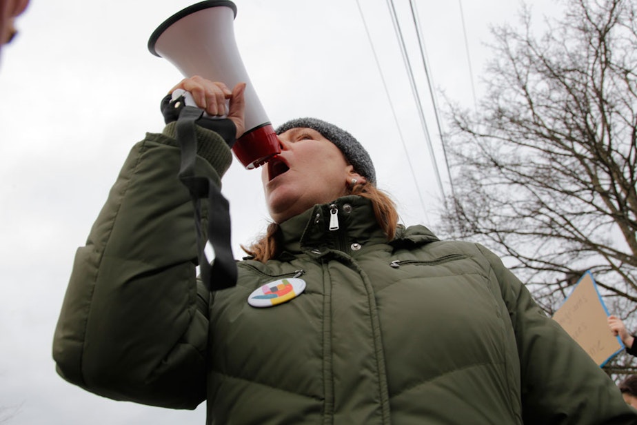 caption: Leslie Brown, an activist with Edmonds Neighborhood Action Coalition, shouted into a bullhorn to rally dozens of protesters gathered outside the Edmonds PCC, January 29, 2017. 