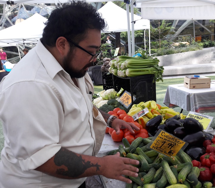 caption: Chef Jay Guerrero checks out the vegetable stand at the Denny Regrade farmer's market.