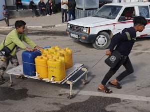 caption: Internally displaced Palestinian children use a makeshift wheeled cart to haul water in Rafah in the southern Gaza Strip on Sunday, as battles continue between Israel and the militant group Hamas.