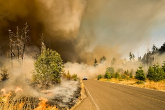 caption: A truck speeds away from the scene of a burgeoning fire.