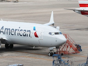 caption: Two grounded American Airlines Boeing 737 Max 8s are seen parked in Miami in 2019. The airline industry is seeing more travelers than in March and April but faces a long road to recovery.