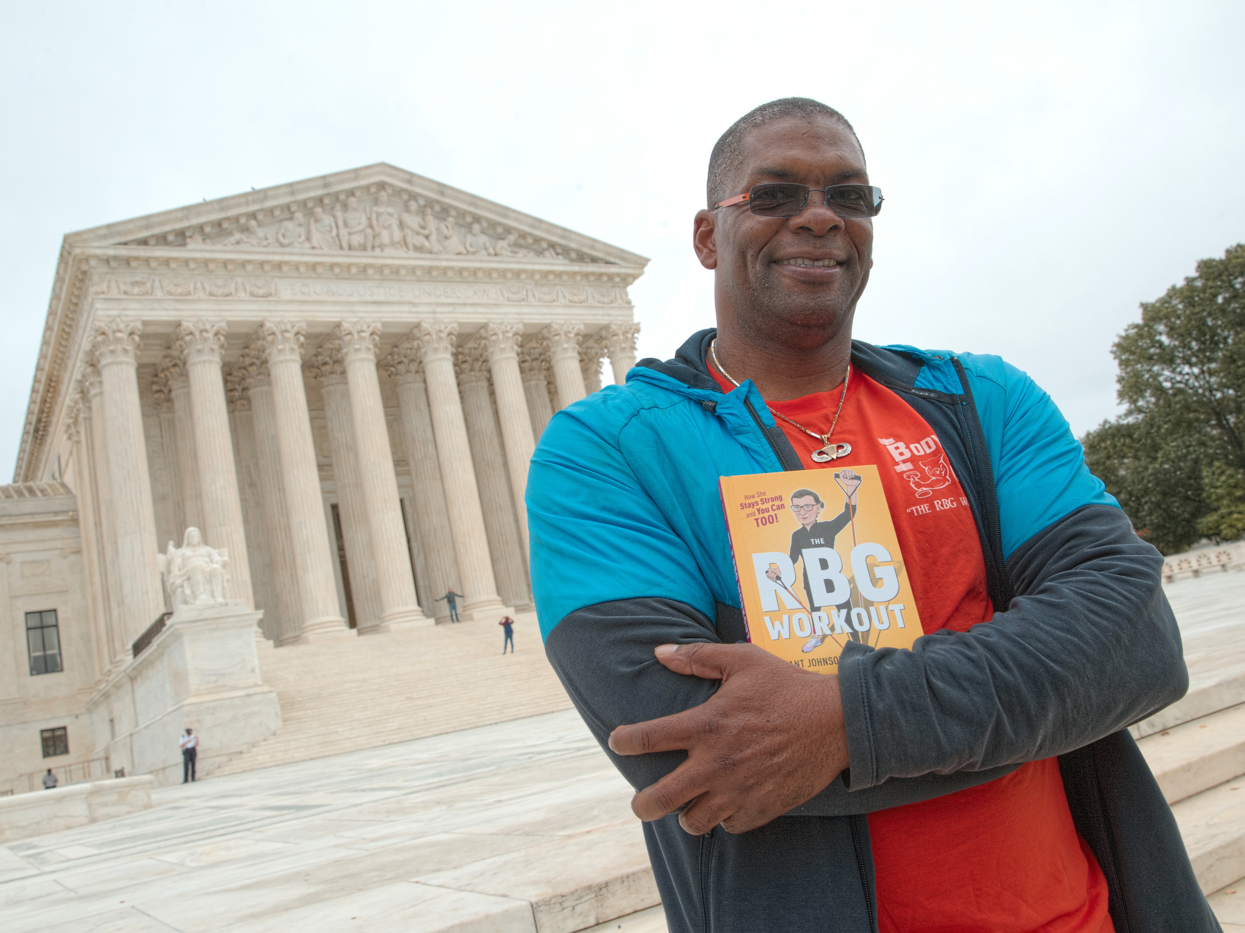 caption: Bryant Johnson, who was Justice Ruth Bader Ginsburg's personal trainer, poses at the court in 2017 with his book, "The RBG Workout: How She Stays Strong ... and You Can Too!"