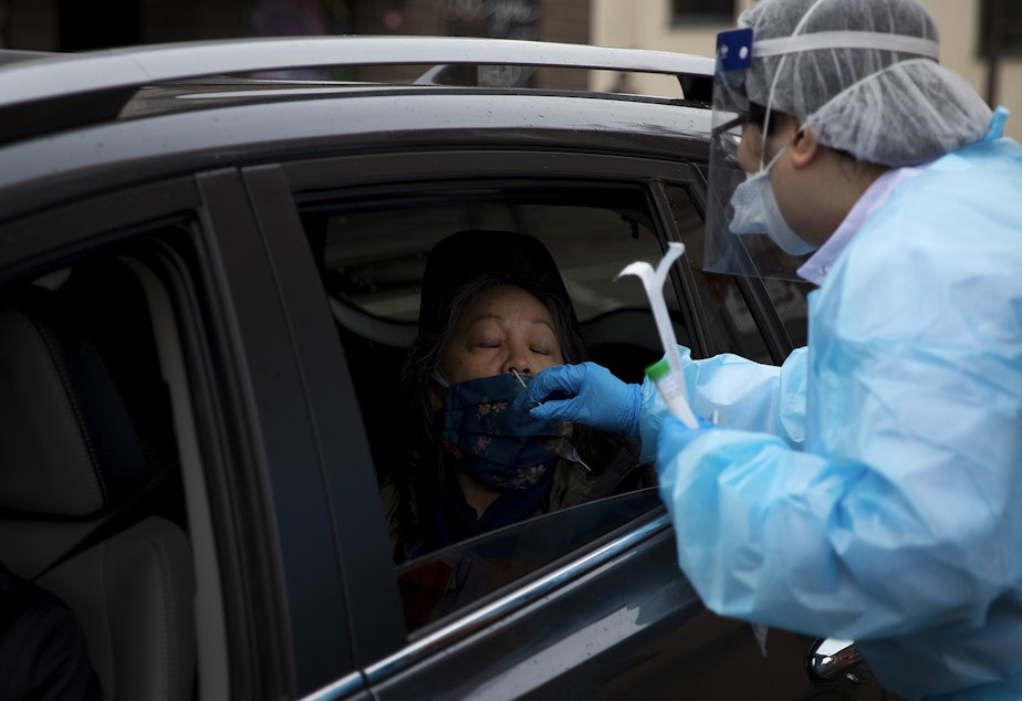 caption: Registered nurse Tina Nguyen administers a Covid-19 test on Friday, November 20, 2020, at the International Community Health Services drive thru testing site on 8th Avenue South in Seattle's International District. 