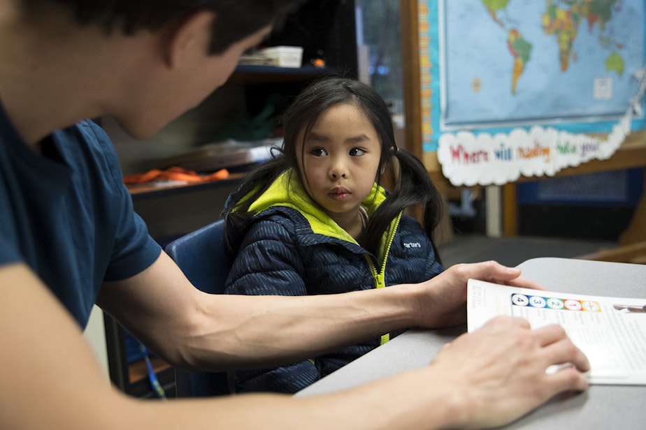 caption: Volunteer Anthony Lee reads with Elizabeth Rith on Wednesday, Jan. 24, 2018, at Sanislo Elementary School in West Seattle. 