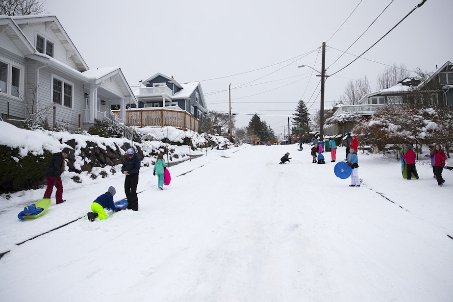caption: A group of kids gather at the intersection of 70th and 2nd Streets to sled on Monday, February 11, 2019, in Seattle. 