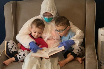 caption: Dr. Lauren Jenkins reads to her twin sons, Pierce and Ashton, while wearing her "hazmat" suit. Because lung cancer has compromised her husband's immune system, Jenkins moved out of her home and visited in the suit as a precaution.