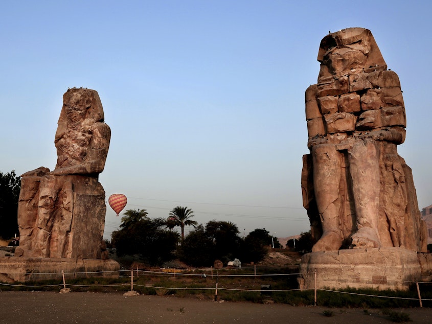 caption: The Colossi of Memnon, two sandstone statues of Amenhotep III, are seen in Luxor in 2017. Excavators say they have discovered a new ancient tomb in the Egyptian city.