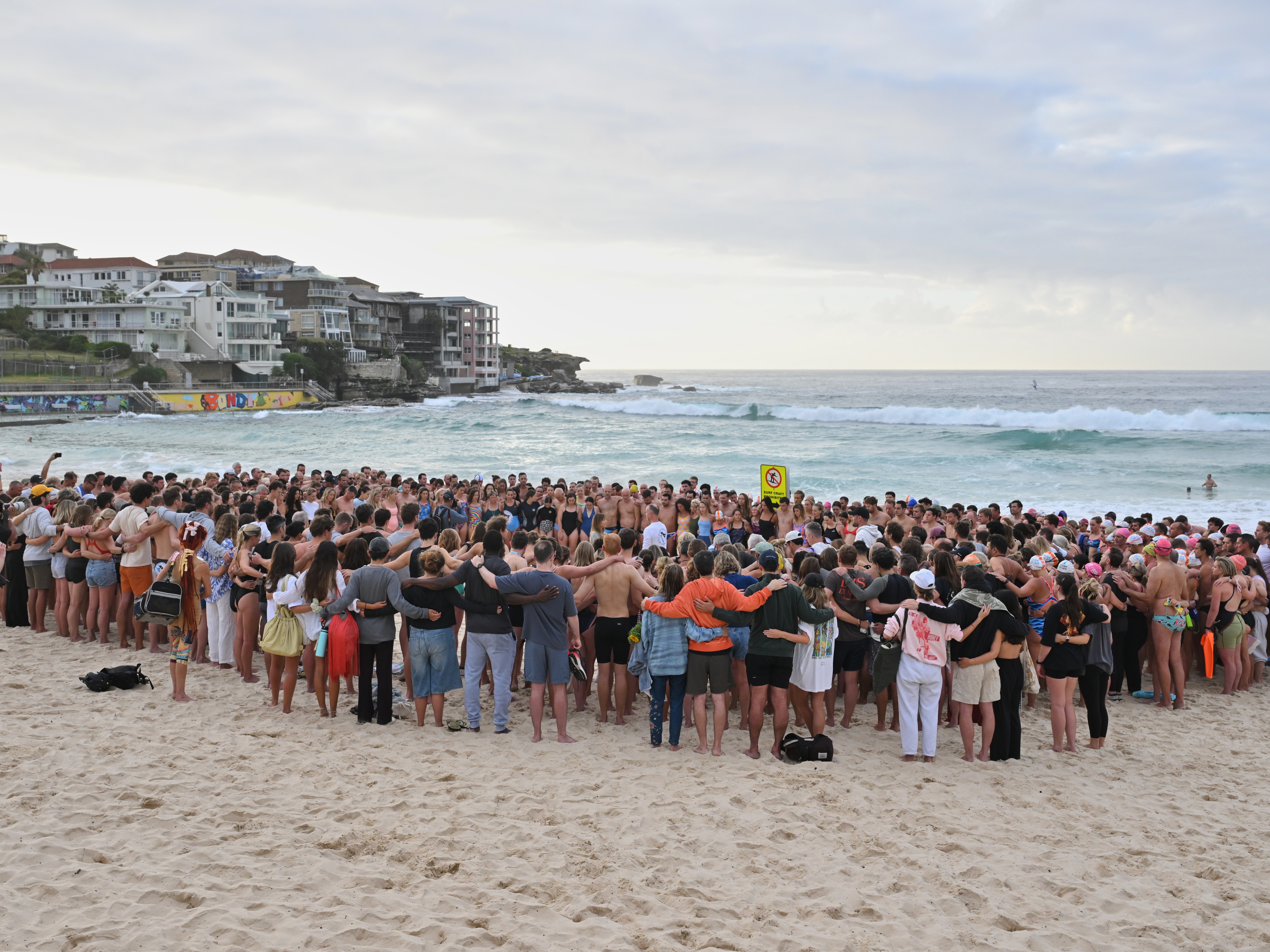 caption: Swimmers gather for a morning vigil in Sydney, Wednesday, Dec. 17, 2025, following Sunday's shooting at Bondi Beach.