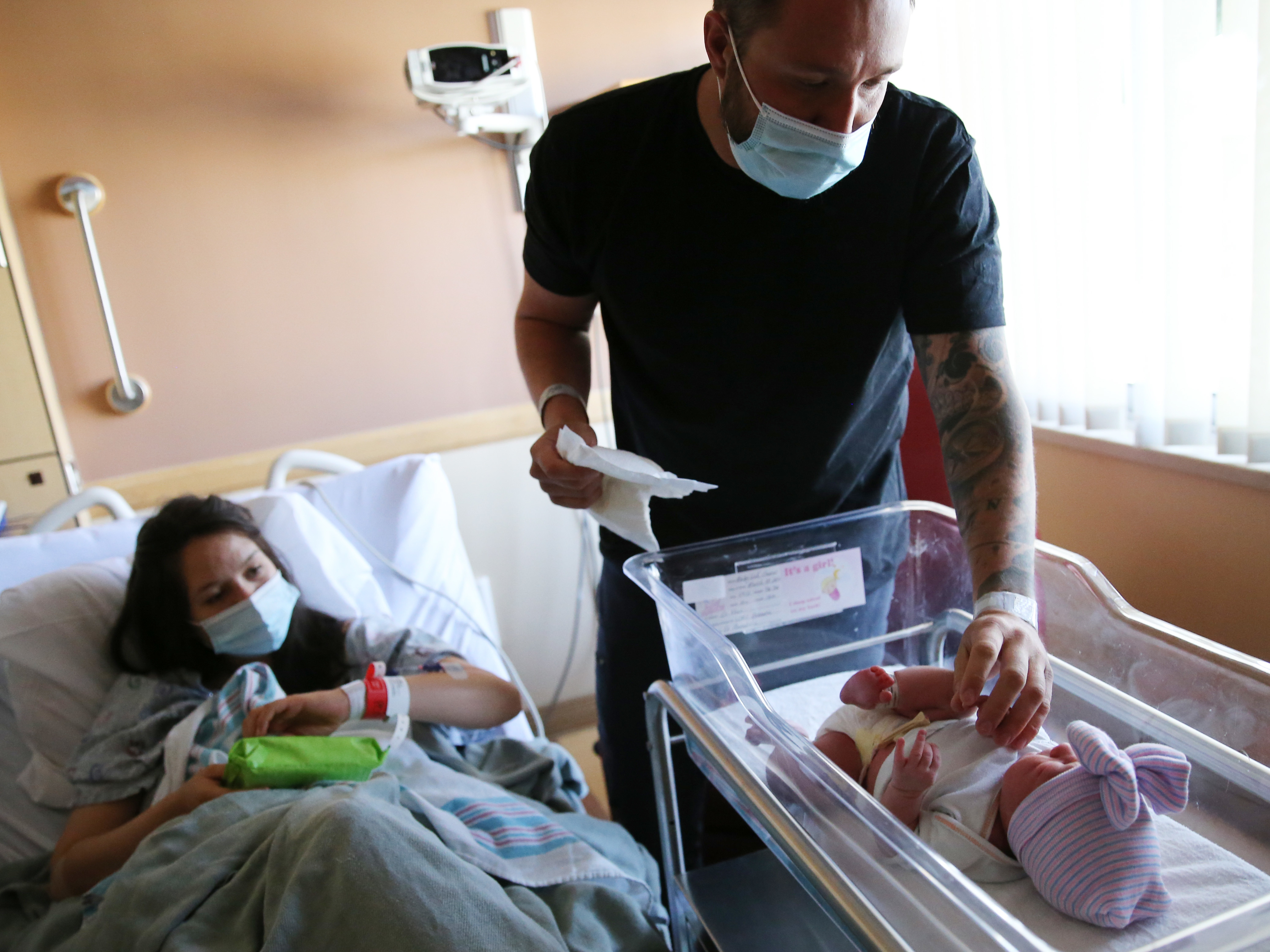 caption: Matthew Carnes prepares to change diapers for his newborn daughter Evelina Carnes as his wife Breanna Llamas keeps watch in the postpartum unit at Providence St. Mary Medical Center in Apple Valley, Calif., in March. The U.S. has reported another record low in its birth rate.