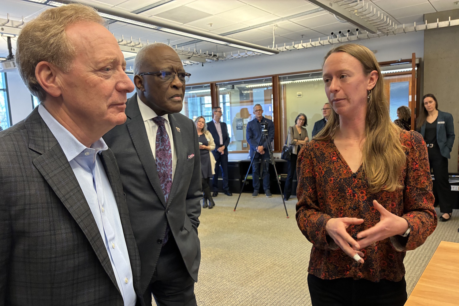 caption: Amelia Keyser-Gibson from the School of Environmental and Forest Sciences (right) speaks with UW President Robert Jones (center) and Microsoft President Brad Smith (left) about her AI-driven environmental research.