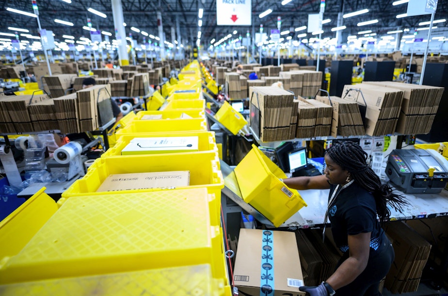 caption: A woman works at a packing station in Amazon's fulfillment center in Staten Island. (Johannes Eisele/AFP via Getty Images)