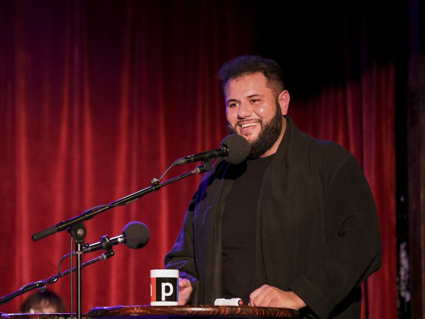 caption: Comedian Mo Amer appears on <em>Ask Me Another</em> at the Bell House in Brooklyn, New York