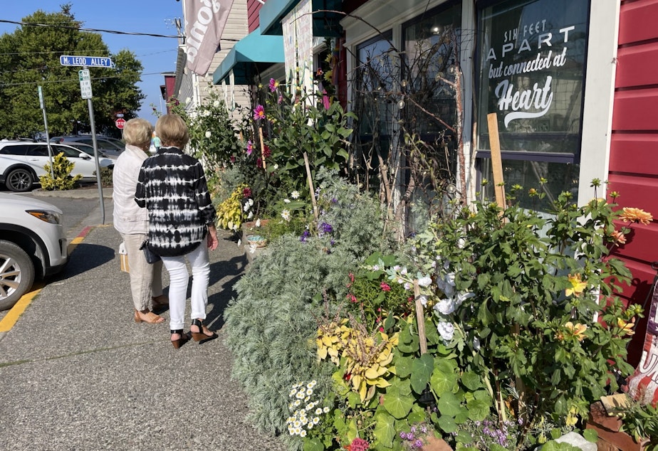 caption: Pedestrians look at flowers and shop in downtown Langley.