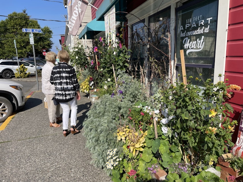 caption: Pedestrians look at flowers and shop in downtown Langley.