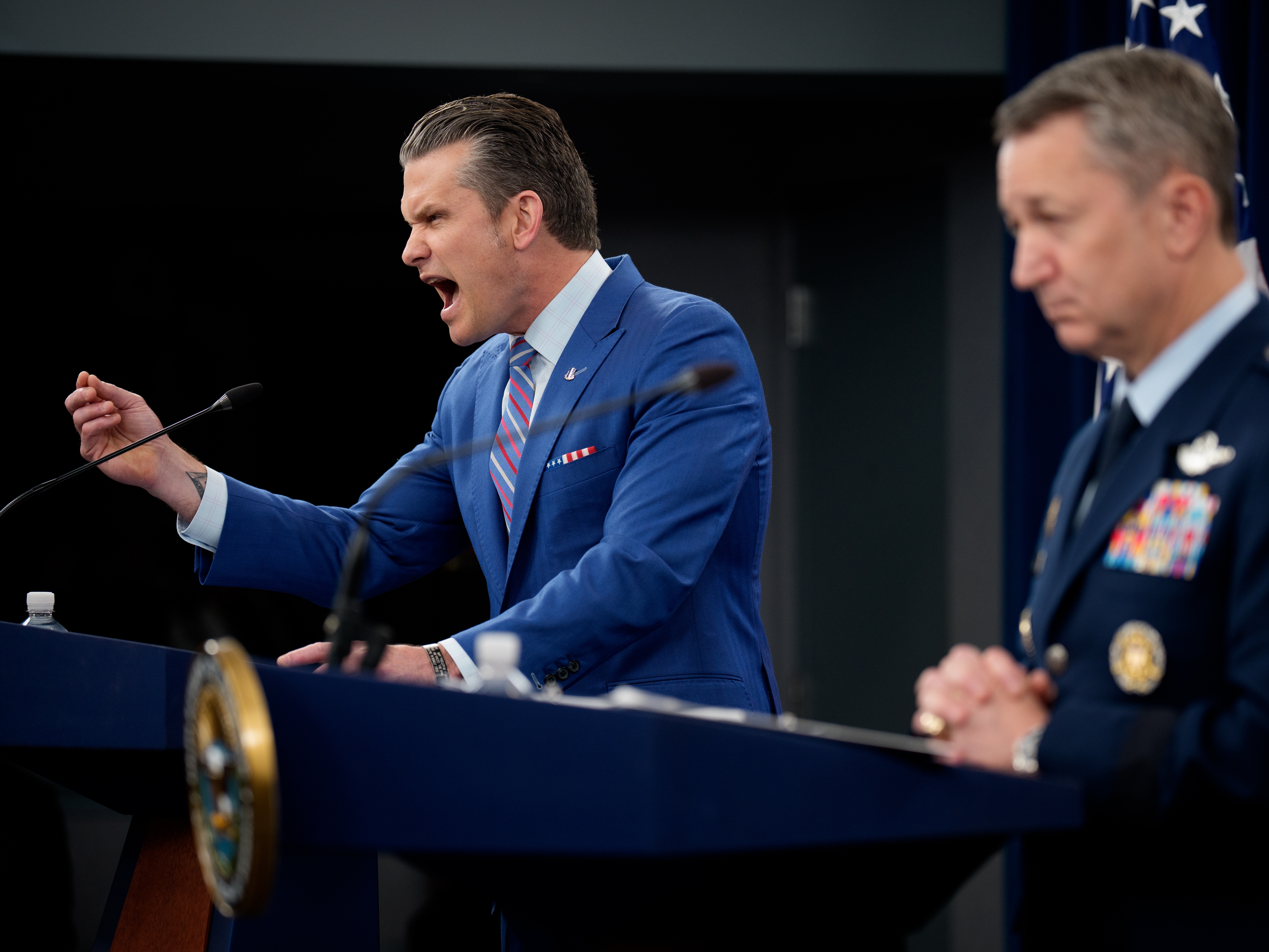 caption: Defense Secretary Pete Hegseth (L), accompanied by Chairman of the Joint Chiefs of Staff Air Force Gen. Dan Caine (R), speaks during a news conference at the Pentagon on Thursday about the U.S. airstrikes against Iran's nuclear facilities.