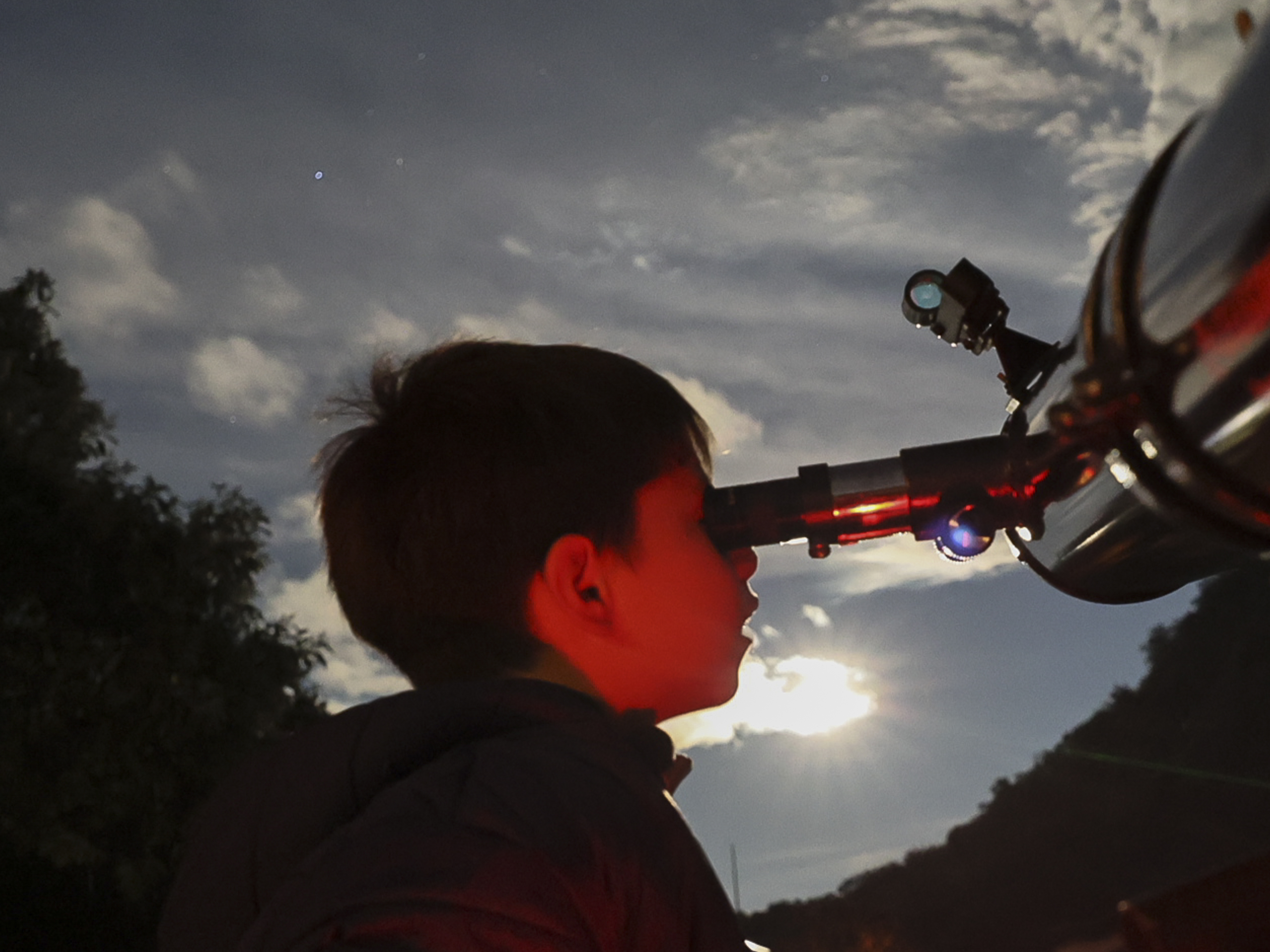 caption: A youth looks through a telescope during a stargazing and comet-watching gathering at Joya-La Barreta Ecological Park in Queretaro, Mexico, on Oct. 19, 2024.